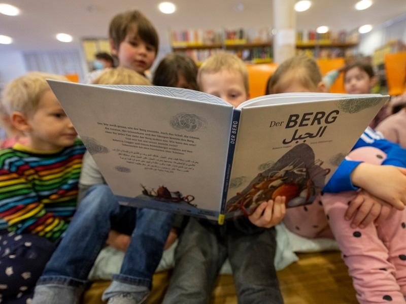 Kinder blicken in das Buch "Der Berg".