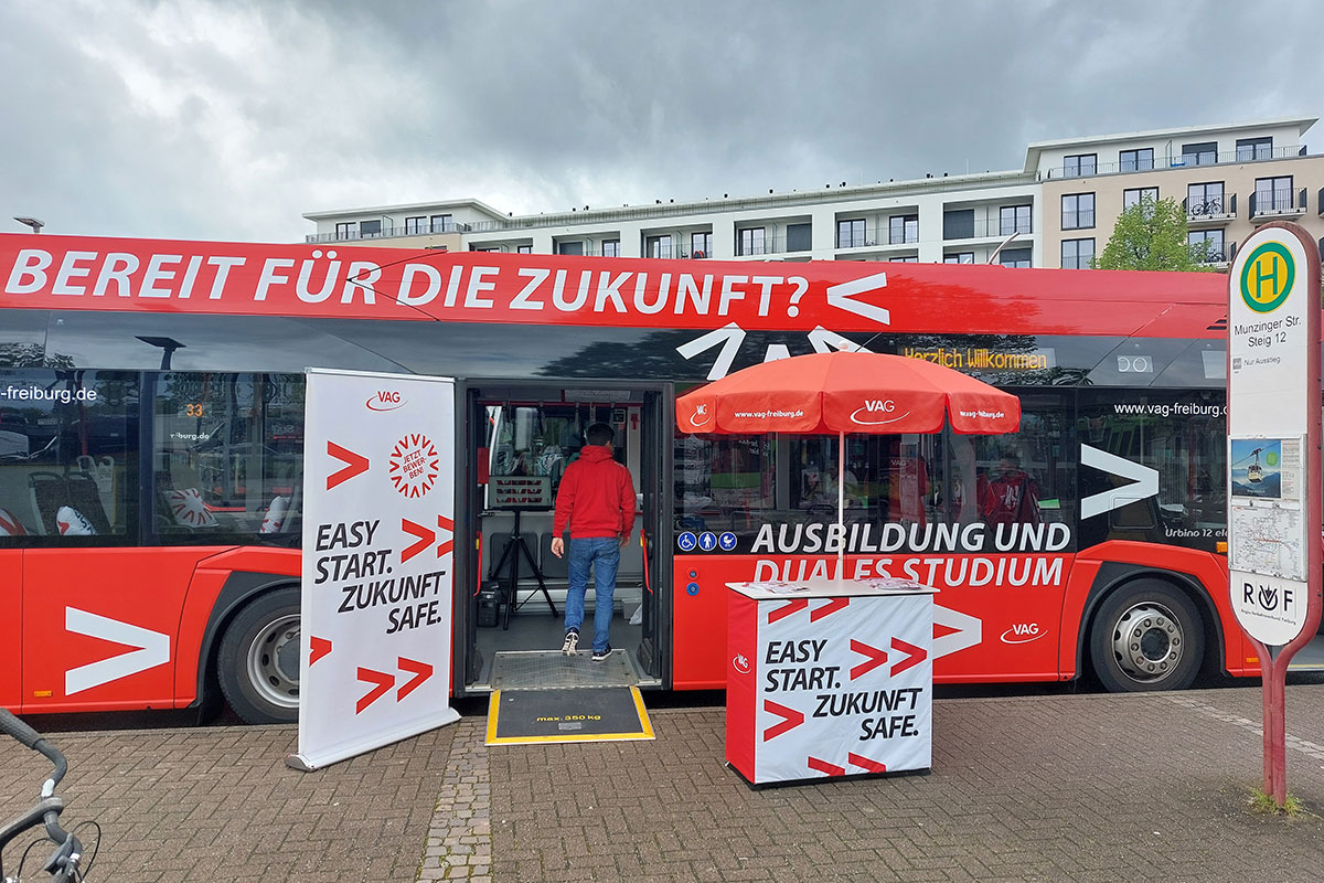 Roter VAG-Bus mit Slogan "Bereit für die Zukunft?", davor ein Infostand