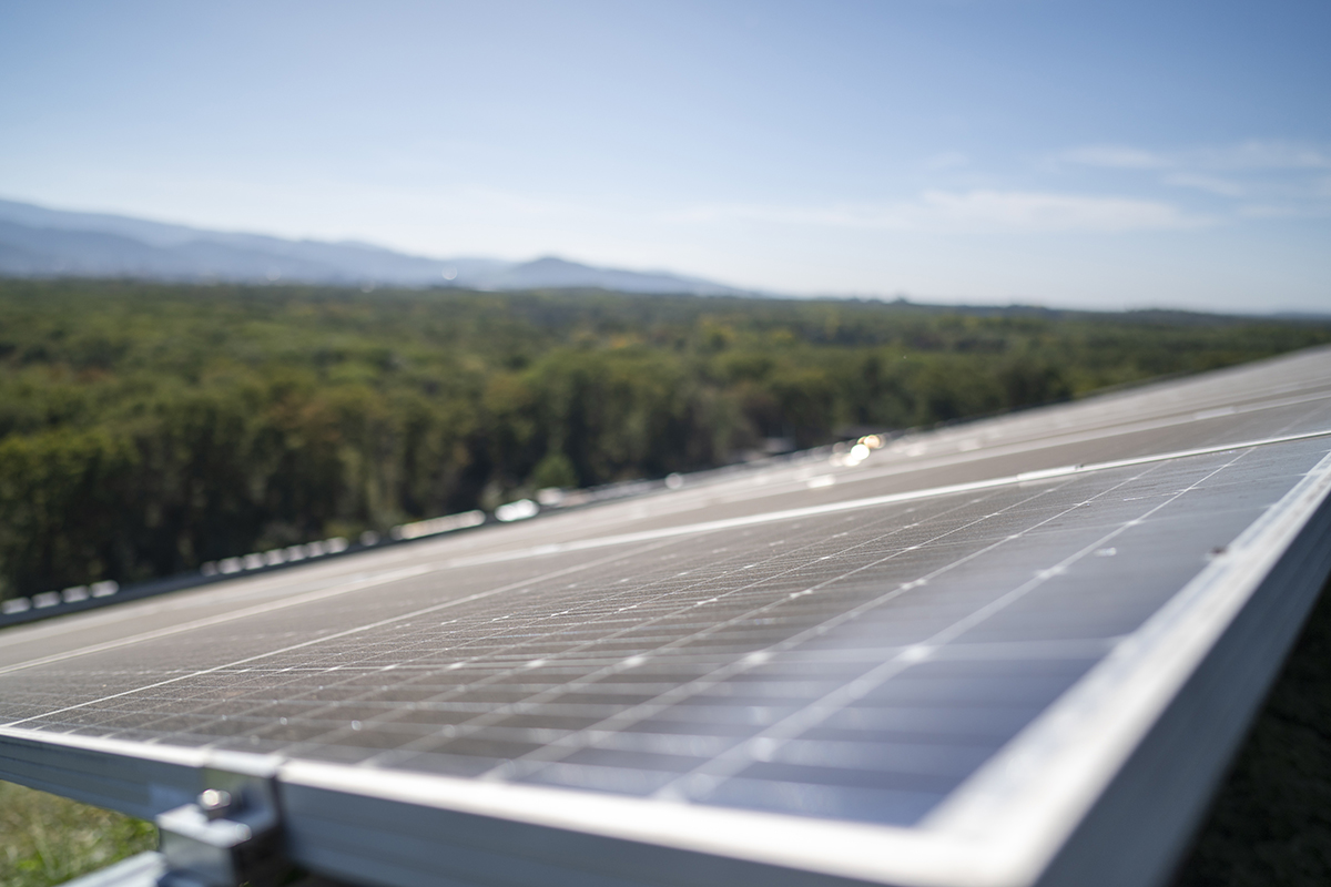 Photovoltaikanlage auf einem Hausdach - im Hintergrund grüne Naturlandschaft