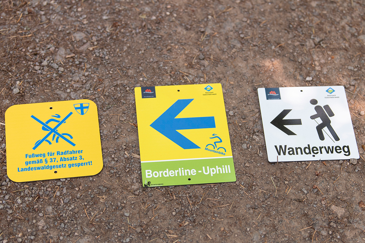 Drei Schilder: Fußweg für Radfahrer gesperrt / Mountainbikestrecke / Wanderweg