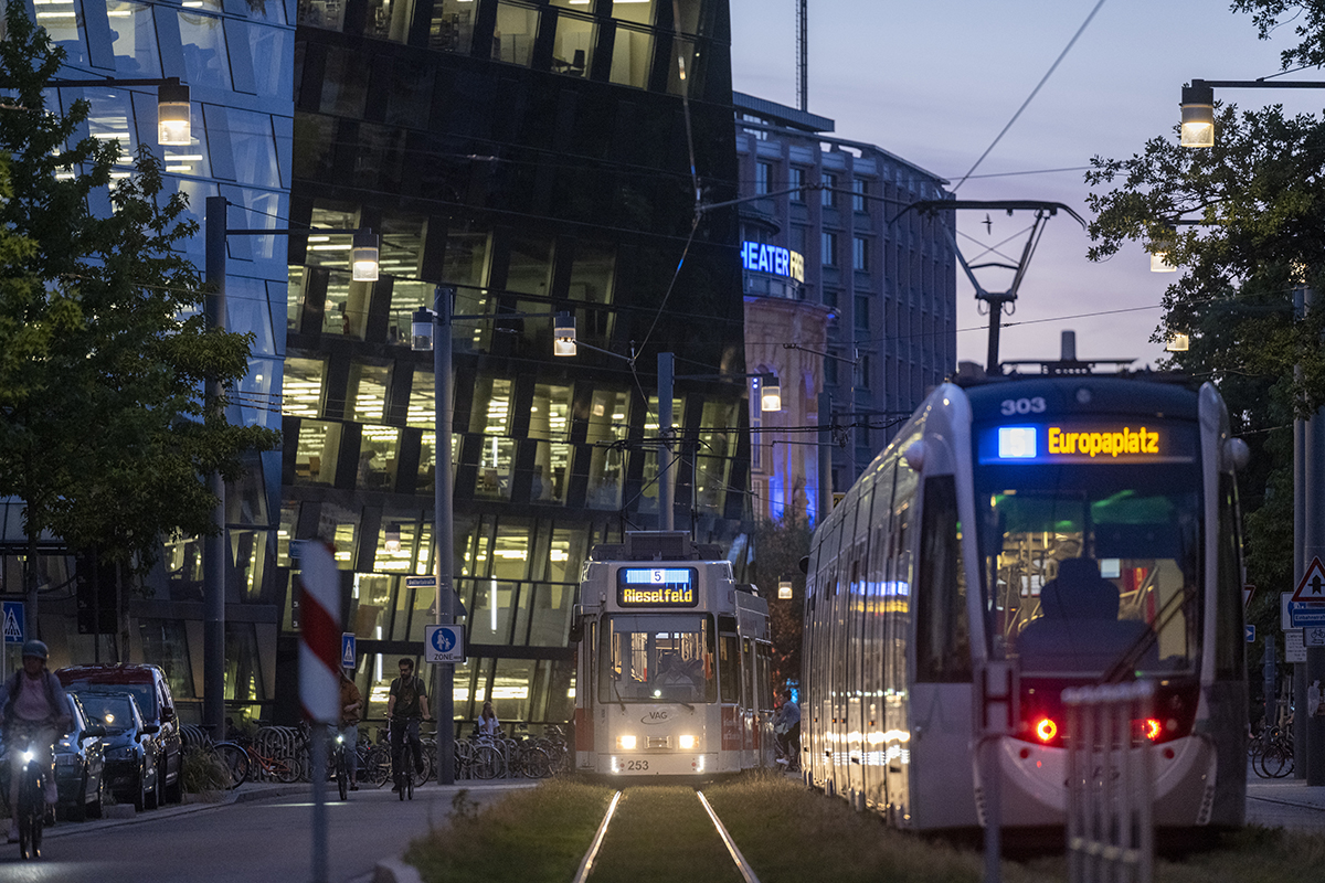 Zwei Straßenbahnen fahren vor der Freiburger Universitätsbibliothek