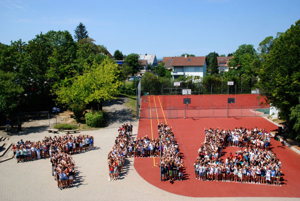 Schülerinnen und Schüler stellen die Buchstaben ihrer Schule "THG" auf dem Sportplatz nach. (Foto: M. Herms)