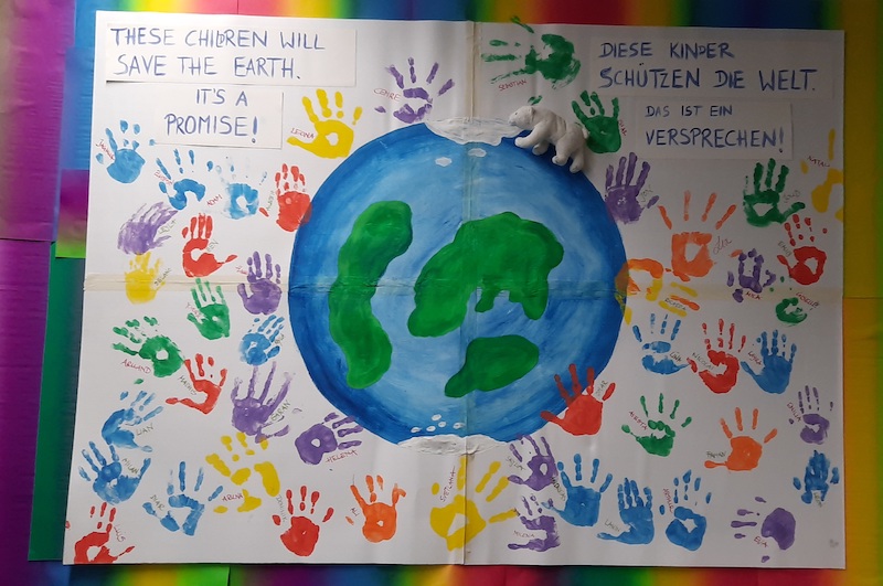 Ein Plakat mit der Erde und Handabdrücken der Kinder.