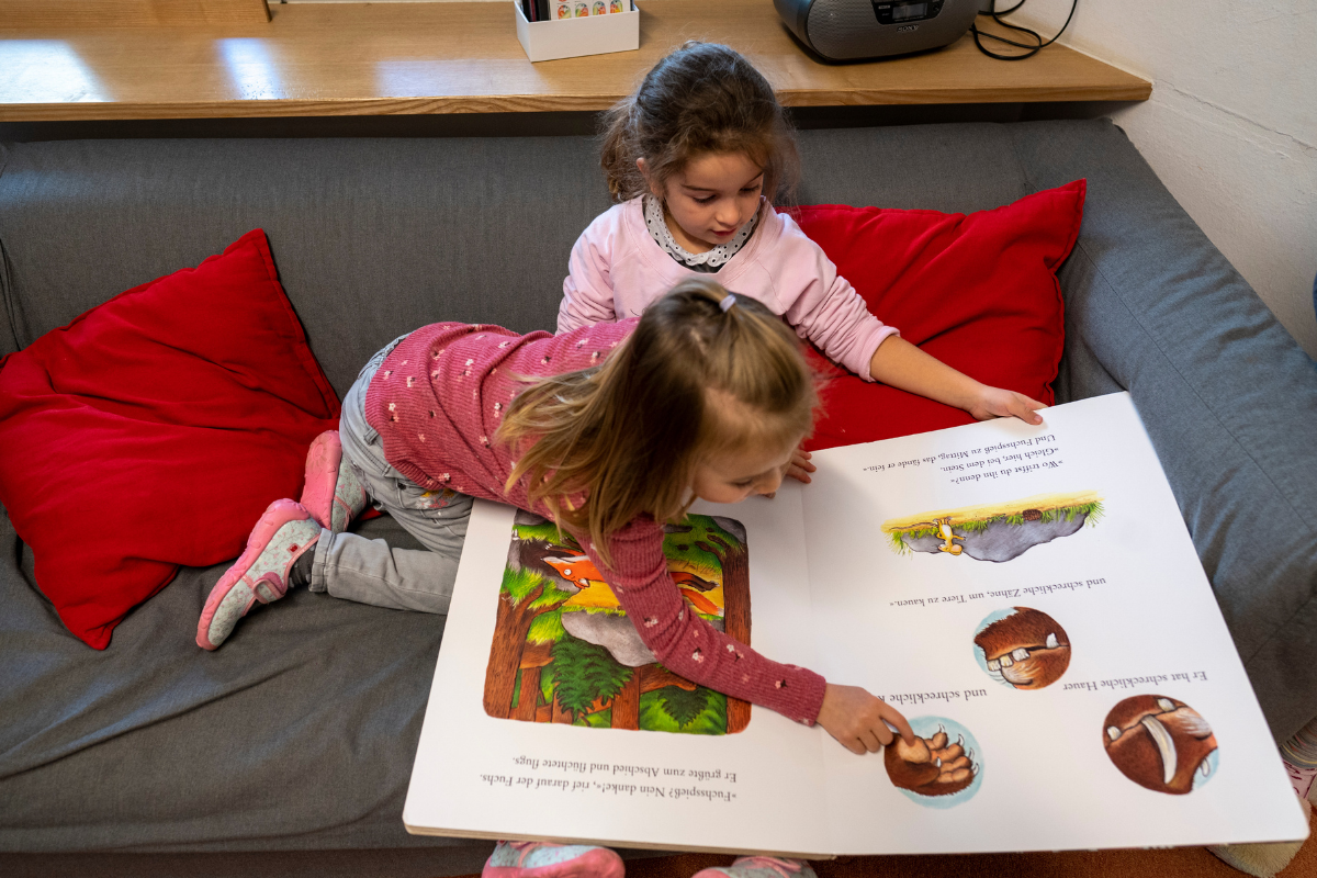 2 Kinder betrachten ein großes Bilderbuch.