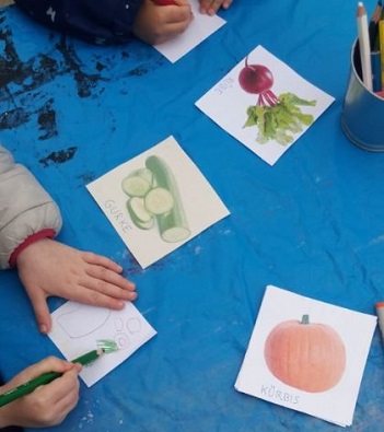 Kinder malen Bilder von Gemüsesorten aus.