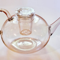 Eine gläserne Teekanne mit leichter rosa Färbung.