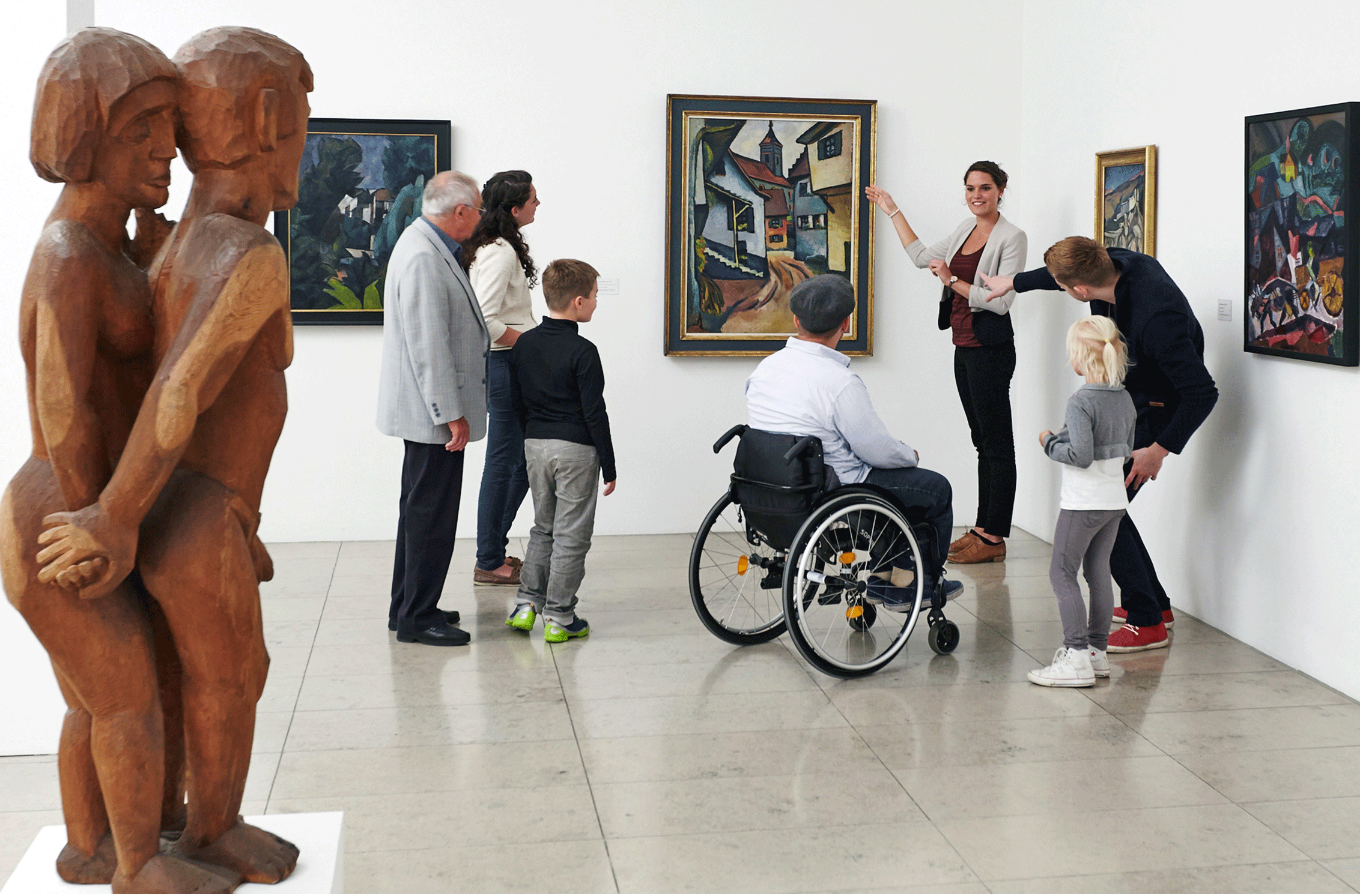 Blick in die Dauerausstellung des Museums für Neue Kunst. Personen betrachten ein Gemälde und bekommen dazu Informationen von einer Frau.