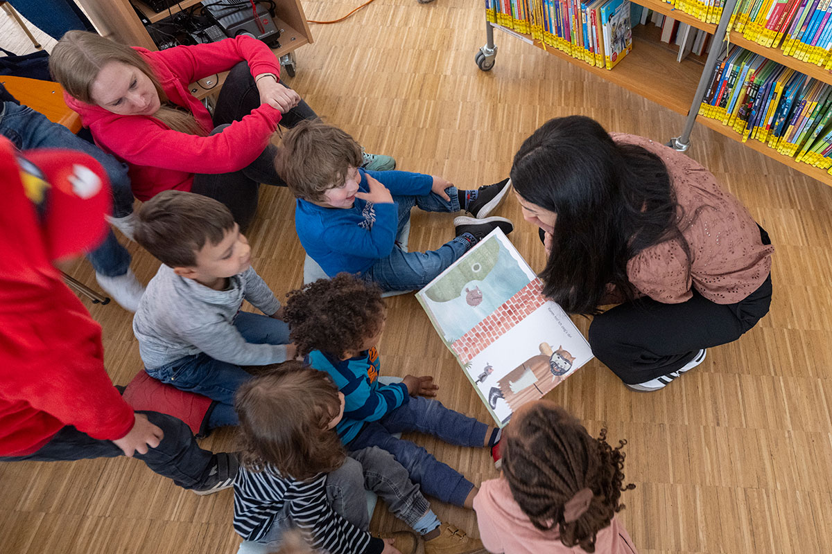 Frau zeigt vier Kindern ein Bilderbuch