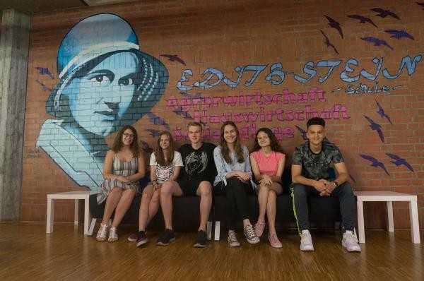 Schülerinnen und Schüler vor einem Edith Stein Graffiti an der Schule