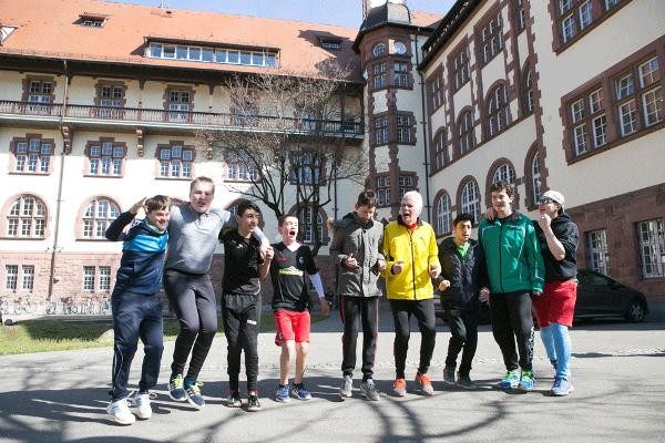 Einige Schüler springen mit ihrem Klassenlehrer vor dem Marathon-Training freudig in die Höhe.  (Foto: A. J. Schmidt)