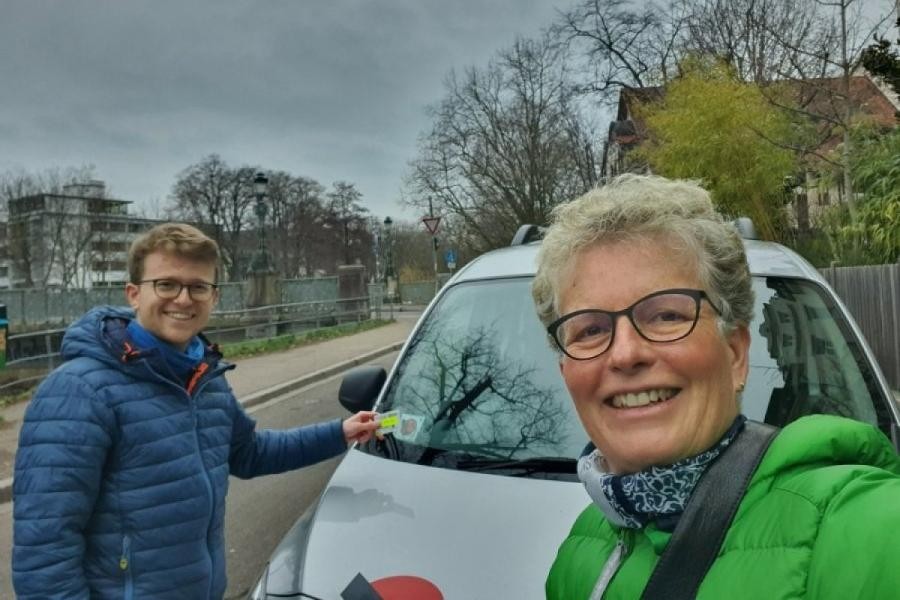 Selfie von einer Mutter mit erwachsenem Sohn und einem Carsharing Auto im Hntergrund