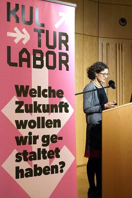 Ina Rüdenauer vom Ökoinstitut hält einen Vortrag neben dem Banner des Kulturlabors