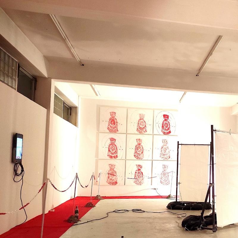 Ausstellungsansicht mit ringsumlaufendem roten Teppich, 9 Gemälden mit roten Geldsäcken im Fadenkreuz, Video und leeren "Werbetafeln"