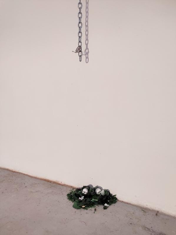 Kunstwerk von Nils Weiligmann, an Kette hängende Sektflasche an Wand zerborsten, Scherben zusammengekehrt
