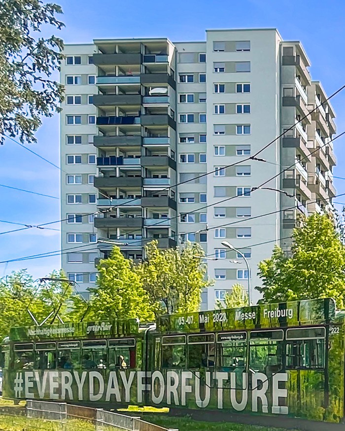Hochhaus, davor grüne Straßenbahn mit Aufschrift Everyday for future