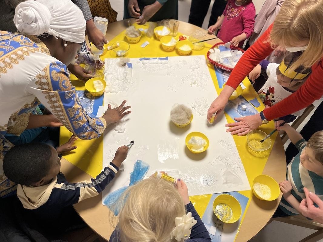 Kinder gestalten mit ihren Familien gemeinsam eine Leinwand.