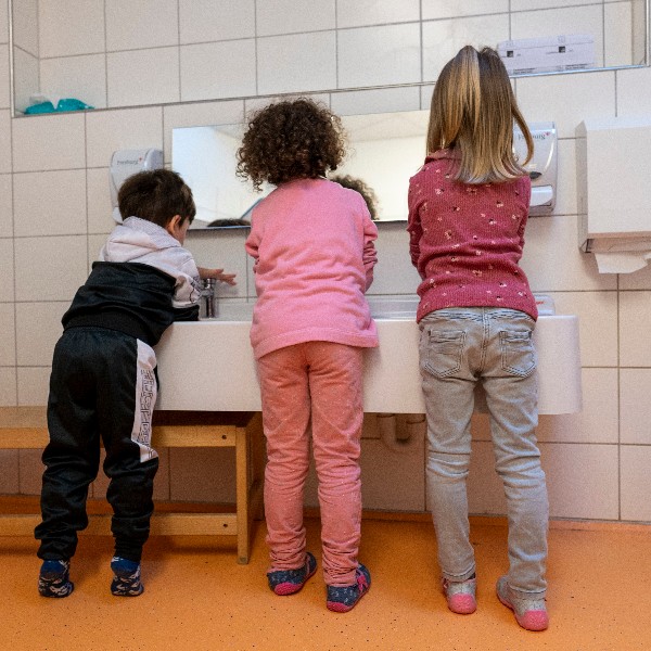 Drei Kinder unterschiedlicher Körpergröße waschen gemeinsam Hände.