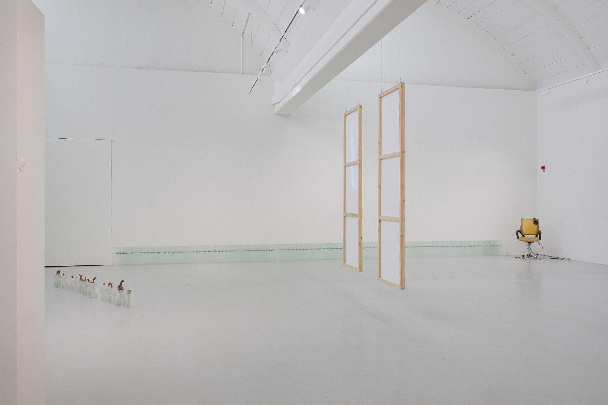 Ausstellungsansicht mit Arbeiten der drei Künstlerinnen Dimæ (hängende Videoinstallation), Marguerite Kalt (mit Latex Bezogener Bürostuhl), Yeun-Kyung Kim (Installation mit 28 Händen aus Kristall und Kupfer und eine zweite Installation mit Gläsern in der das Wort "Ende in verschiedenen Sprachen steht)