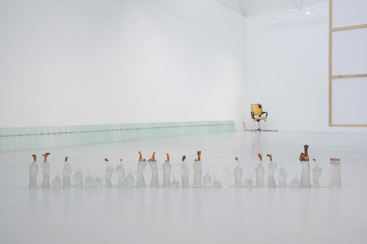 Ausstellungsansicht mit dem Kunstwerk "SILENT SLOGAN" von Yeun-Kyung Kim im Vordergrund: Kristallhände auf dem Boden, die einen Finger emporstrecken und der durch Elektrolyse mit Kupfer überzogen ist