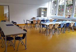Klassenraum mit drei Tischen und bunten Stühlen