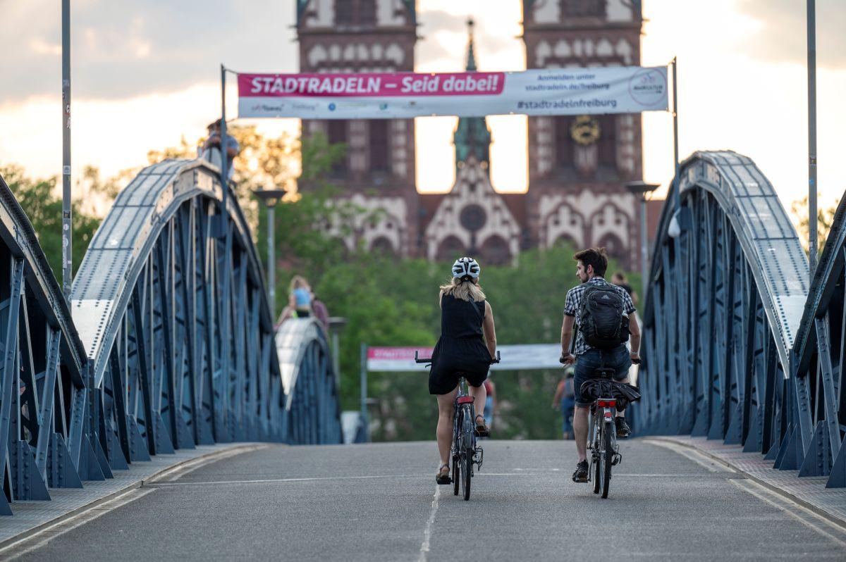 Eine Fahrradfahrerin und ein Fahrradfahrer fahren zusammen über die Wiwili-Brücke unter einem Stadtradeln-Banner durch.