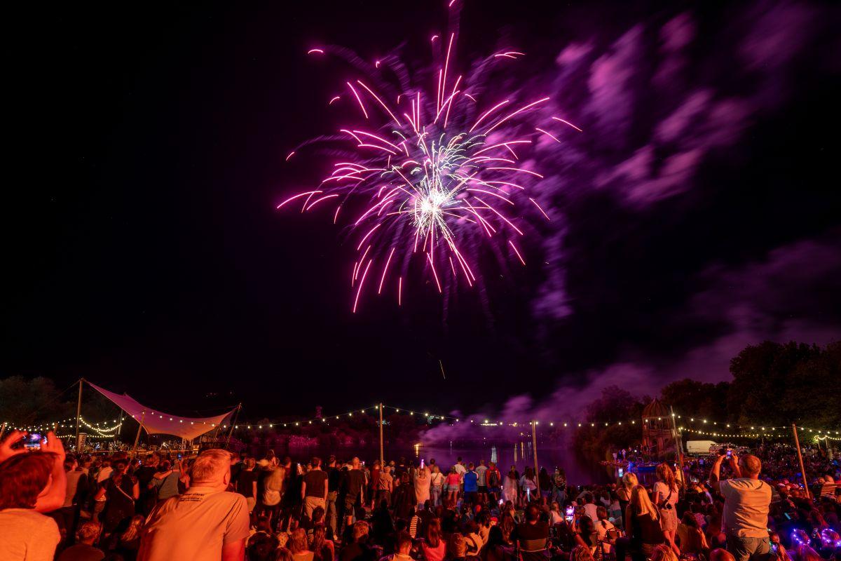Menschen schauen bei Nacht das Feuerwerk am Seepark an.