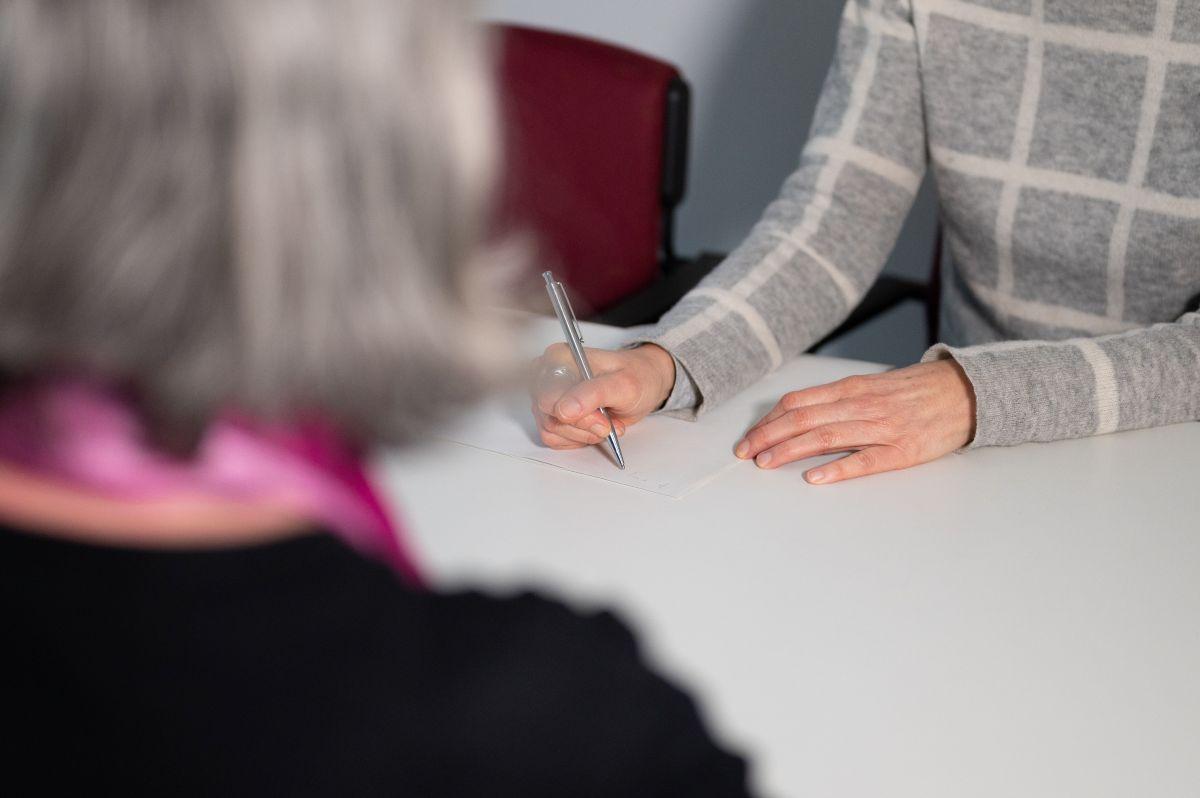 Jemand schreibt mit Hand etwas auf einen Zettel