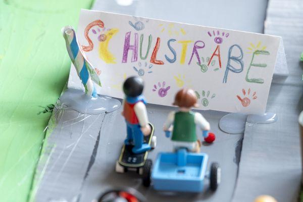 Spielfiguren vor einem Aufsteller mit der Aufschrift "Schulstraße"