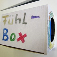 weißer Karton mit Loch vorne und seitlicher Aufschrift " Fühl-Box"