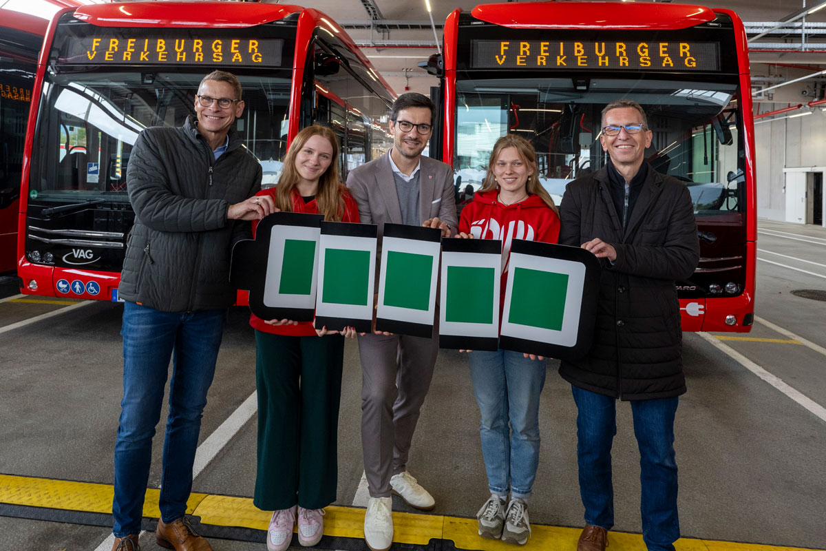 Vier Personen stehen vor E-Bussen