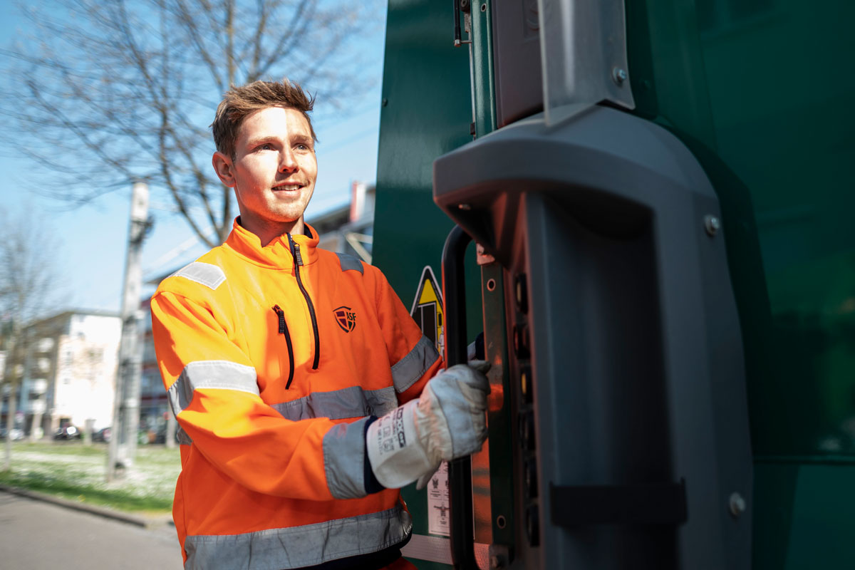 Junger Müllwerker auf einem Müllfahrzeug