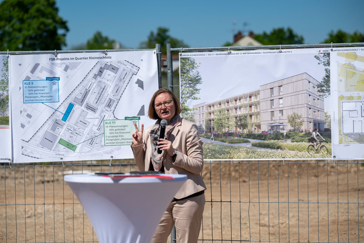 Frau hält Mikro und zeigt die Zahl zwei