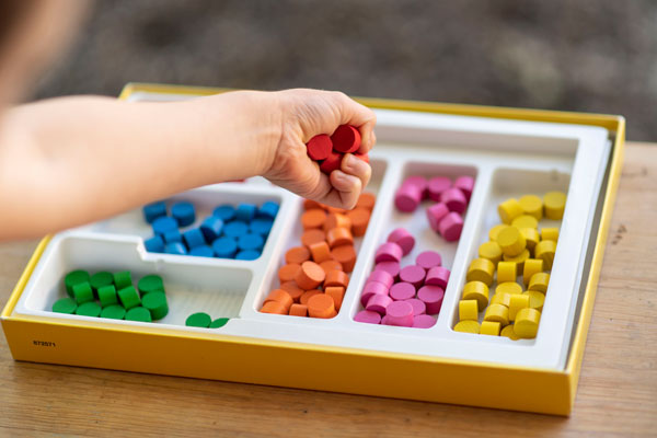 Kinderhand spielt mit bunten Farbsteinen