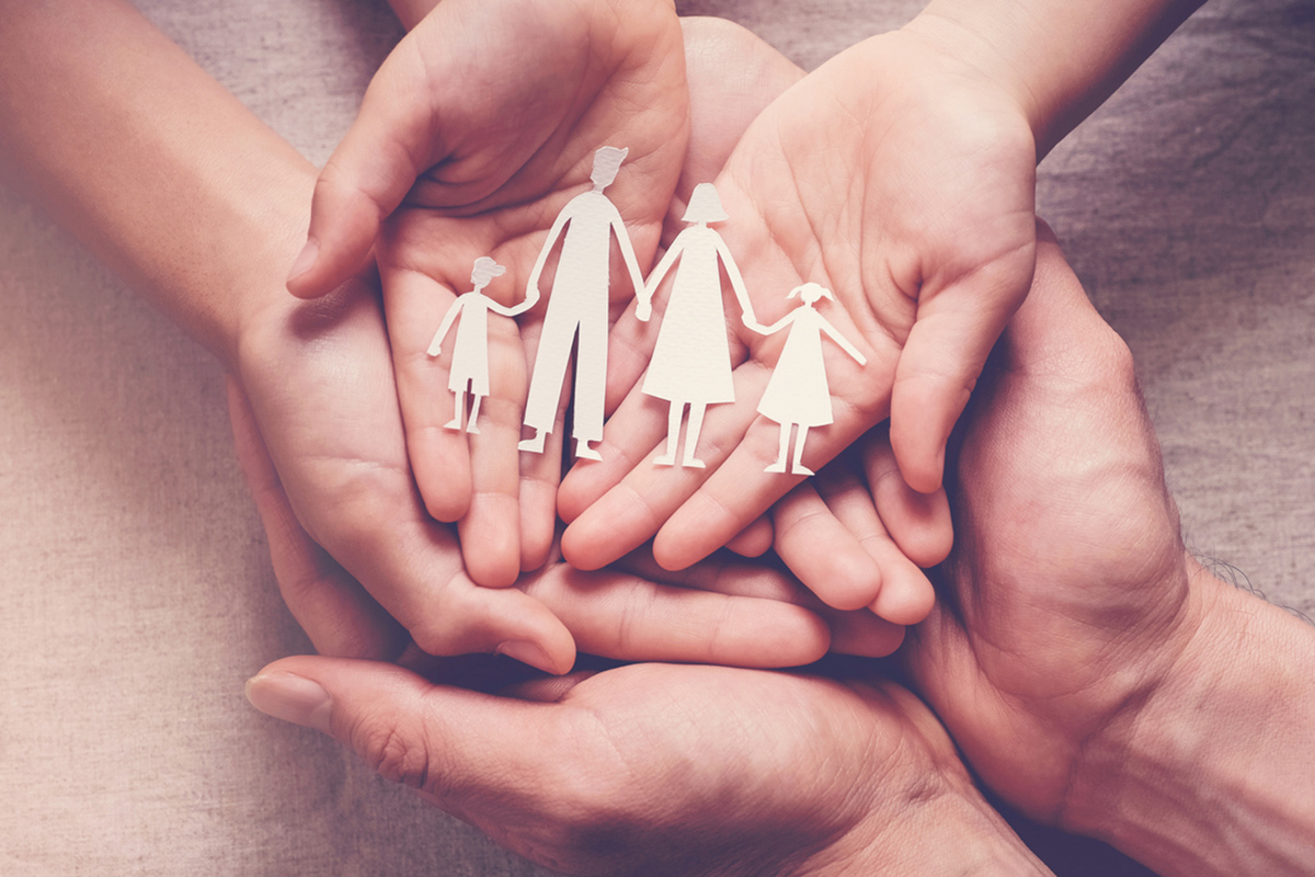 Erziehungsberatungsstellen: Sechs Hände halten eine aus Papier ausgeschnittene Familie