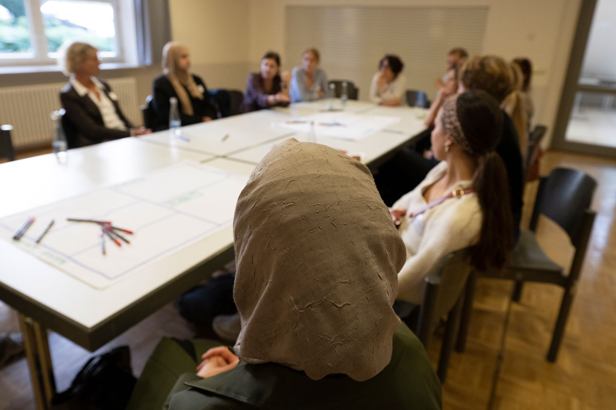 Viele Personen sitzen um einen Tisch und unterhalten sich