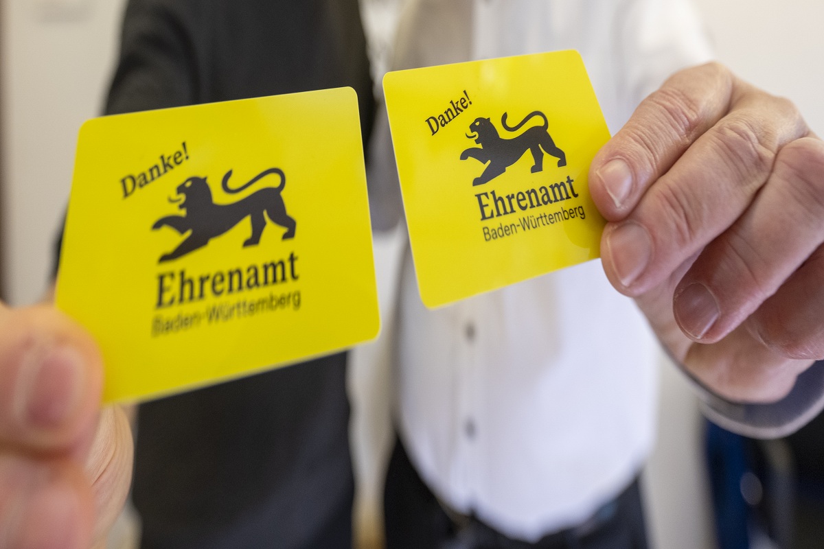 Die Ehrenamtskarte Baden-Württemberg wird von zwei Personen in die Kamera gehalten.