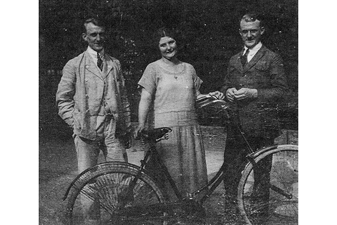 Drei Personen stehen hinter einem Fahrrad