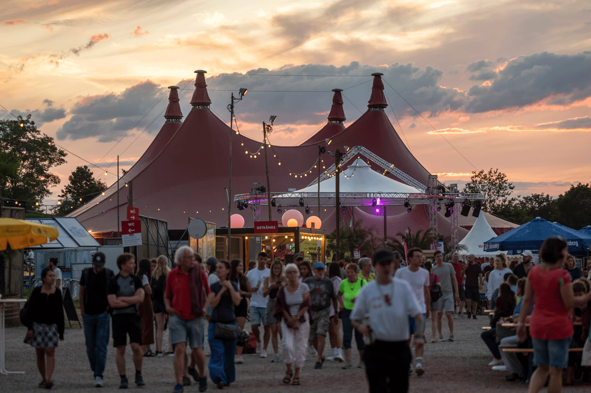 Zirkuszelt auf dem ZMF bei Sonnenuntergang, im Vordergrund Menschen