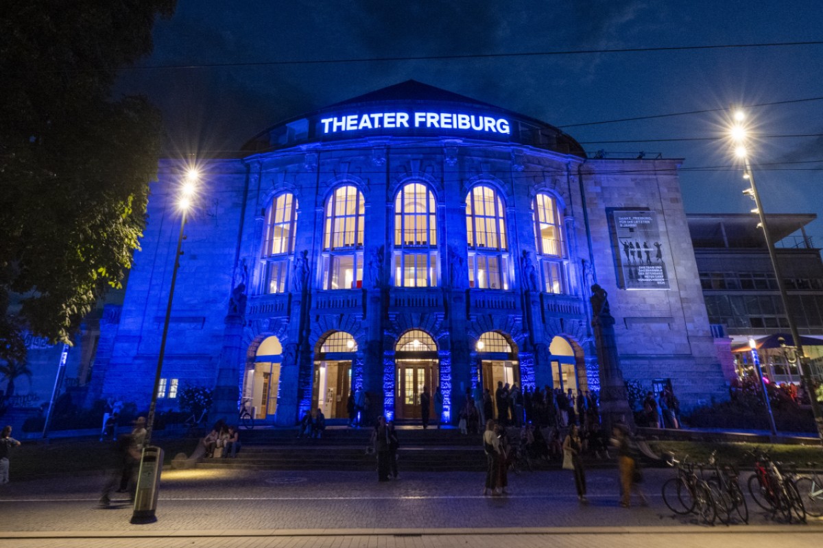 Das blau angestrahlte Theater Freiburg von vorne unten.