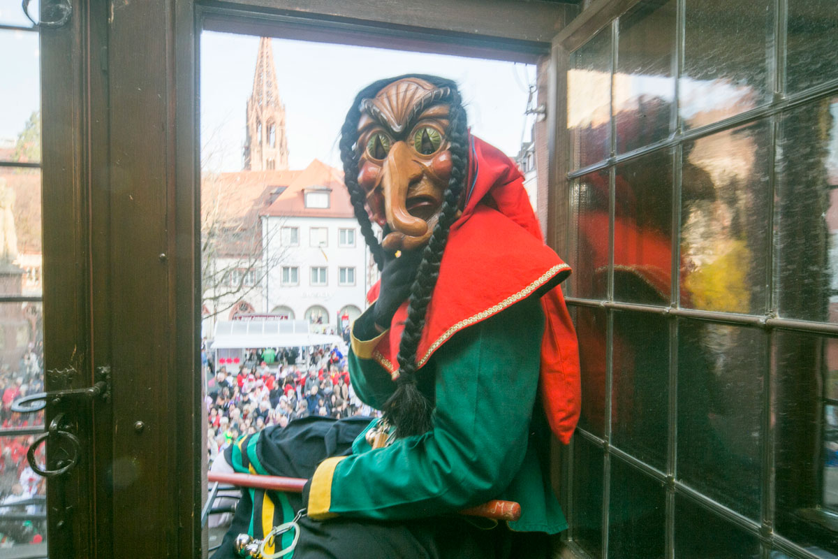 Rathaussturm an Fasnet, verkleidete Hexe sitzt im Fenster des Rathauses
