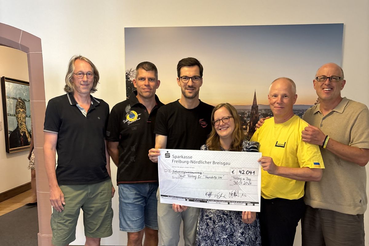 Sechs Personen halten einen großen Spendenscheck in der Hand