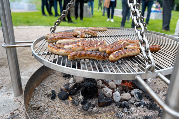 Ein offener Grill mit einigen fertigen Bratwürsten.