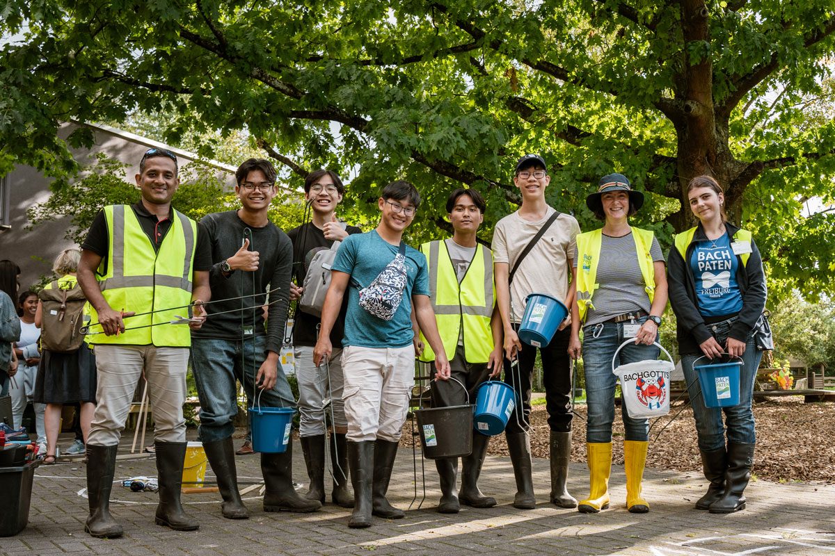 Mehrere Menschen halten Eimer und Zangen für Müll in der Hand