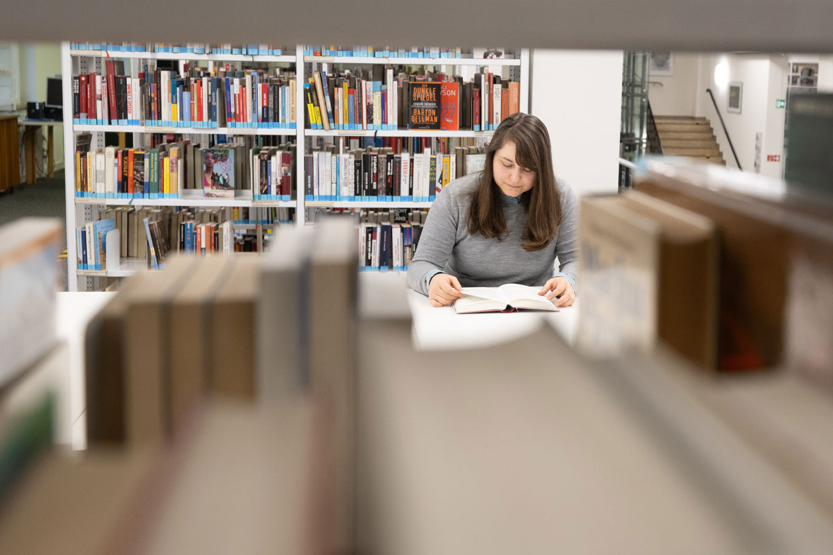 Junge Frau sitzt in der Bibliothek und liest