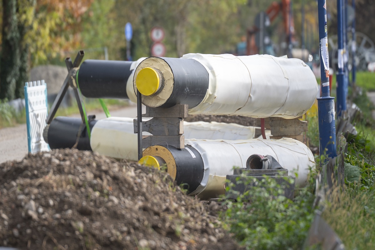 Fernwärmerohre liegen neben der Straße, davor ein großer Erdhügel.