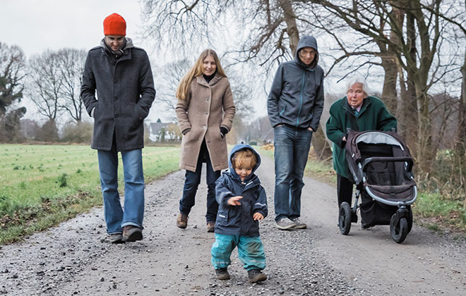 Zwei Männer, eine junge und eine ältere Frau und ein Kleinkind beim Spaziergang.
