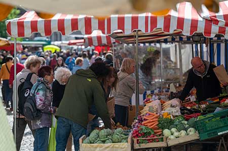 Marktstand mit Gemüse und Einkaufenden