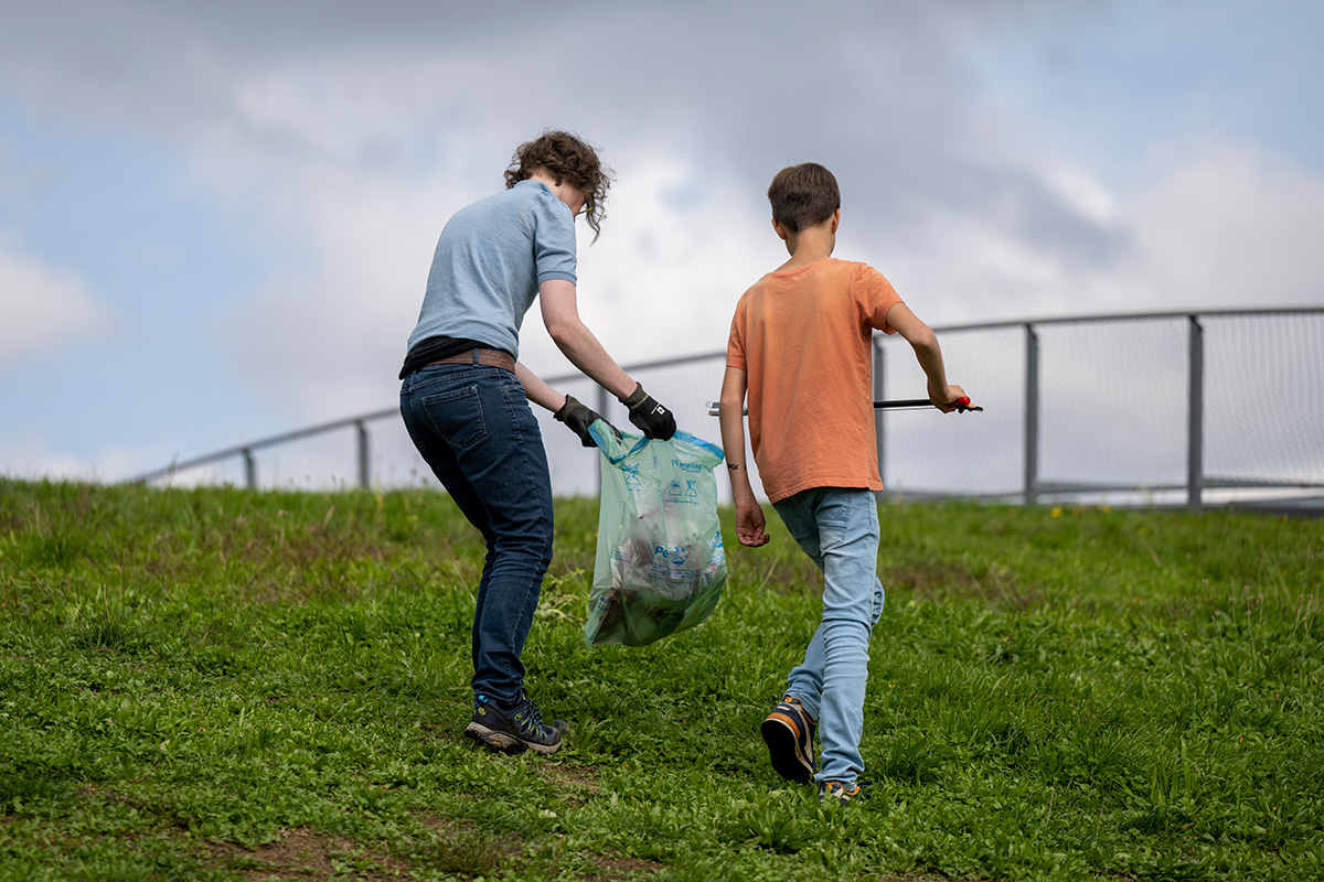 Frau und Junge beim Müllsammeln auf einer Wiese