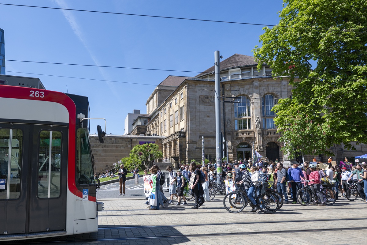 Ein Aufzug von Demonstrierenden läuft einer Straßenbahn entgegen.