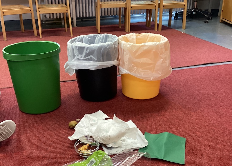 Drei Mülleimer stehen auf dem Boden.